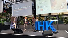 Mike Gahn und Simon Adams präsentieren eine KI-Lösung zur digitalen Pflegedokumentation beim KI-Tag der IHK Köln.