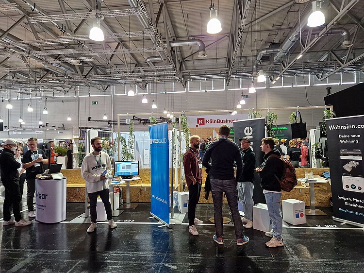 Besucherinnen und Besucher im Gespräch an Messeständen auf der DMEXCO in Köln