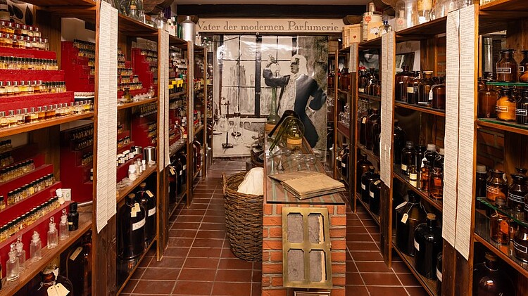 Blick auf Gang mit Regalen auf denen alte Parfümfläschchen stehen.