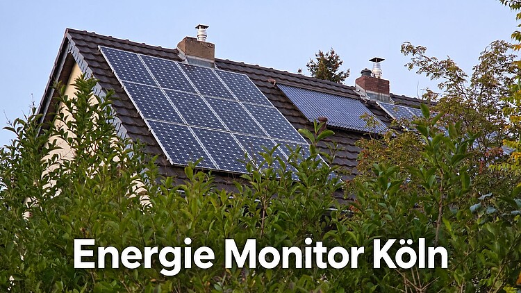 Hausdach mit Photovoltaikanlage und Solarkollektoren, teilweise von grünen Bäumen verdeckt