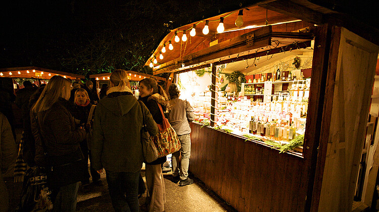 Menschen stehen vor Weihnachtsmarkthütte