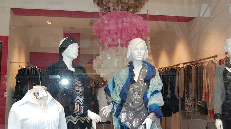 Es sind bekleidete Schaufensterpuppen in einem Schaufenster zu sehen 