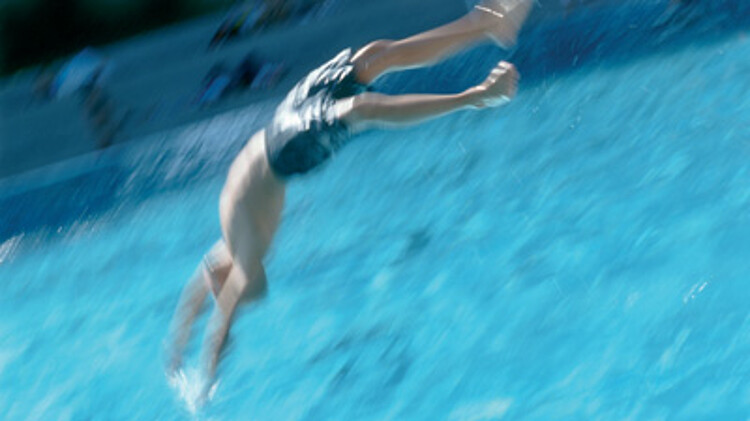 Person springt mit einem Köpper ins Wasser